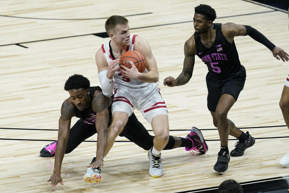 Wisconsin's Brad Davison (34) recovers a loose ball against Penn State's Izaiah Brockington (12) and Jamari Wheeler (5) during the first half of an NCAA college basketball game at the Big Ten Conference tournament, Thursday, March 11, 2021, in Indianapolis. (AP Photo/Darron Cummings)