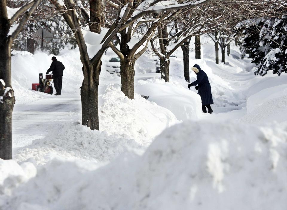 Wayne Neally (L) runs a snowblower to clear his driveway while Deanne Ferguson does her clearing the old-fashioned way with a large snow scoop in Duluth, Minnesota. People from Texas to New York were bundling up December 5 against winter weather that closed schools and businesses, blanketed roads and power lines with ice and threatened to disrupt travel across a wide swath of the United States. REUTERS/Bob King/Duluth News Tribune