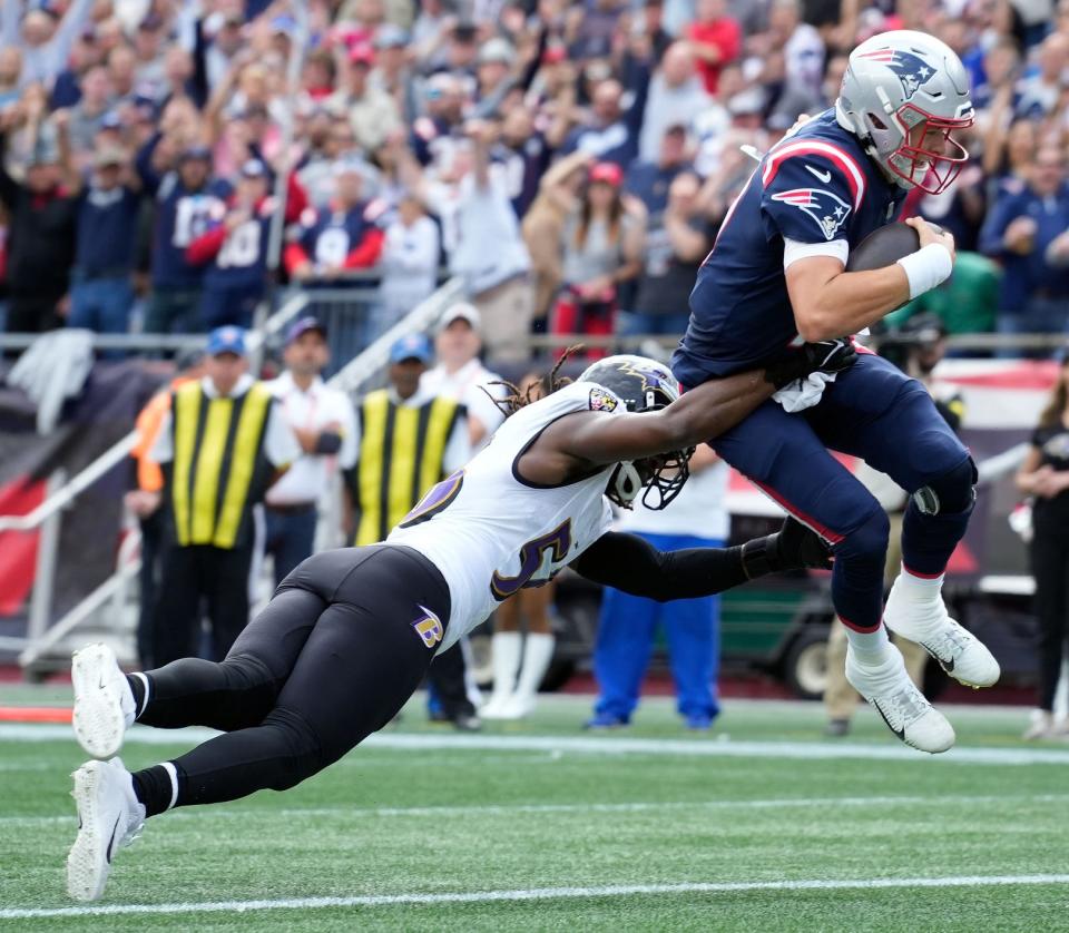 Patriots quarterback Mac Jones scores a touchdown after getting by Baltimore linebacker Josh Bynes during Sunday's game in Foxboro.