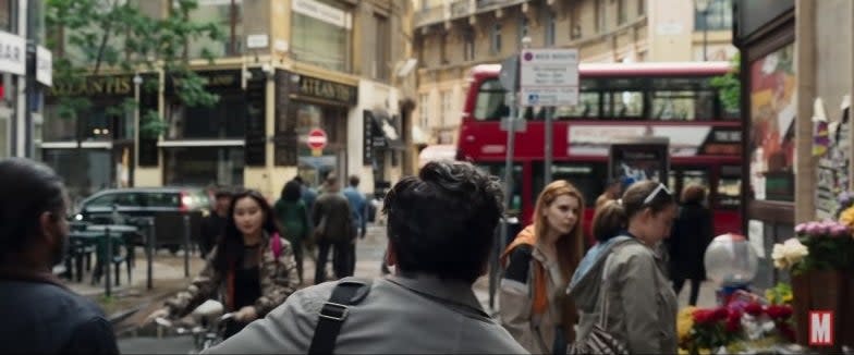 The back of Steven as he runs through a throng of people in a busy London street, a red double decker bus in front of him