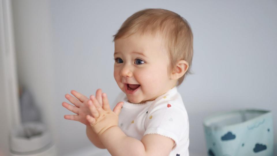 a 1 year old baby girl clapping her hands on her baby changing table