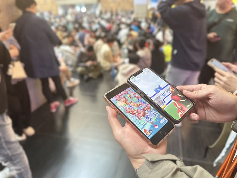 人氣手遊Pokémon GO「原始固拉多團體戰日」23日下午登場，台北車站一樓大廳有百餘名玩家聚集，眾人或坐或站、專注抓寶。（中央社）