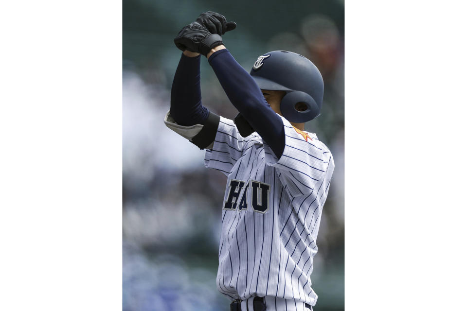 A player for Tohoku High School gestures after getting on first base during their game against Yamanashi Gakuin Senior High School at a stadium in Nishinomiya, Osaka, western Japan Saturday, March 18, 2023. Lars Nootbaar's imaginary pepper-grinder was the talk of World Baseball Classic games in Japan, but the fun-loving gesture by the St. Louis Cardinals outfielder does not appear welcome in Japan's popular high school baseball tournament.(Kyodo News via AP)