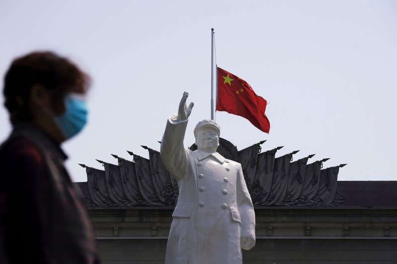 The Chinese national flag flies at half-mast behind a statue of late Chinese chairman Mao Zedong in Wuhan