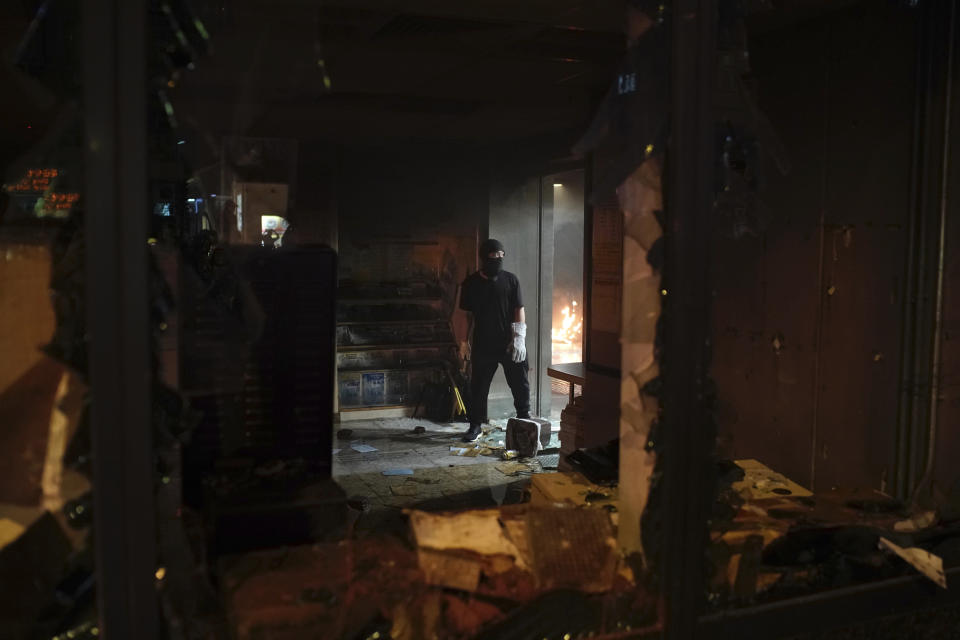 A black-clad protestor stands inside a vandalized government office building in Hong Kong, Tuesday, Oct. 1, 2019. Hong Kong police shot a protester at close range, leaving him bleeding from his shoulder and howling on the ground, in a fearsome escalation of anti-government demonstrations that spread across the semi-autonomous Chinese territory on Tuesday. Tens of thousands marched in a day of rage as Communist leaders in Beijing celebrated 70 years in power. (AP Photo/Felipe Dana)