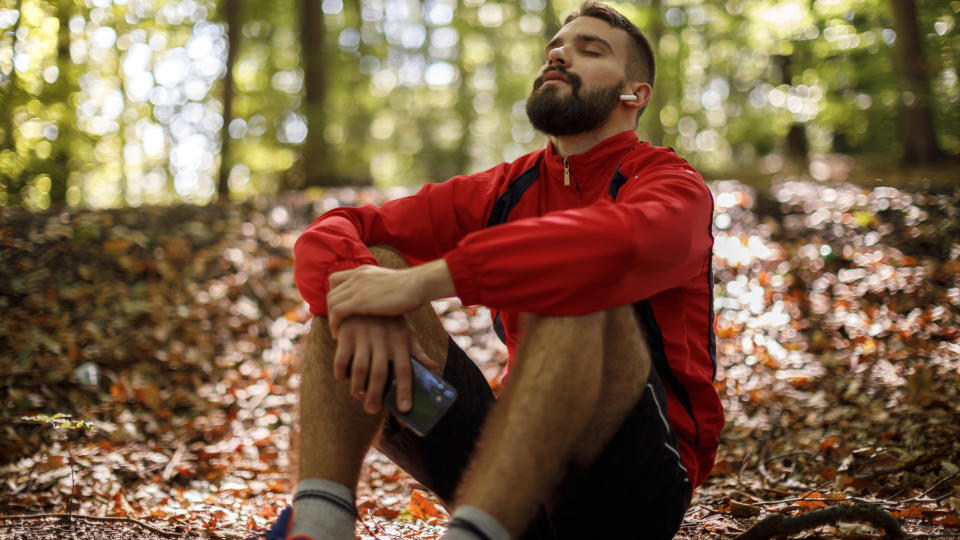 A runner sits and relaxes in a forest