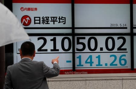 FILE PHOTO: A man points out an electronic board showing the Nikkei stock index outside a brokerage in Tokyo