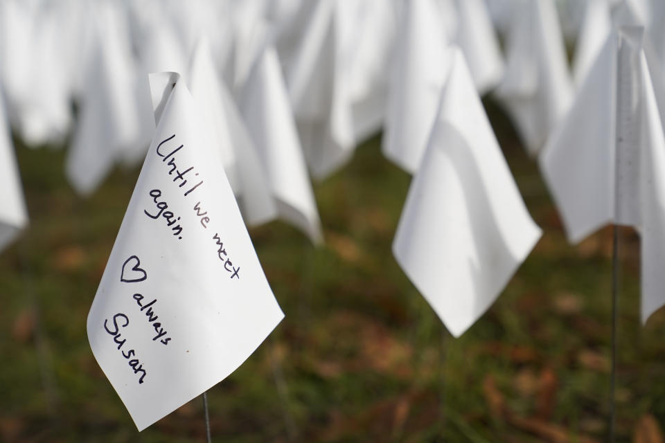 A white flag with a note stands in a temporary art installation in remembrance of Americans who have died of COVID-19, Tuesday, Oct. 27, 2020, near Robert F. Kennedy Memorial Stadium in Washington. Artist Suzanne Brennan Firstenberg's installation, called "In America, How Could This Happen," will include an estimated 240,000 flags when completed. (AP Photo/Patrick Semansky)