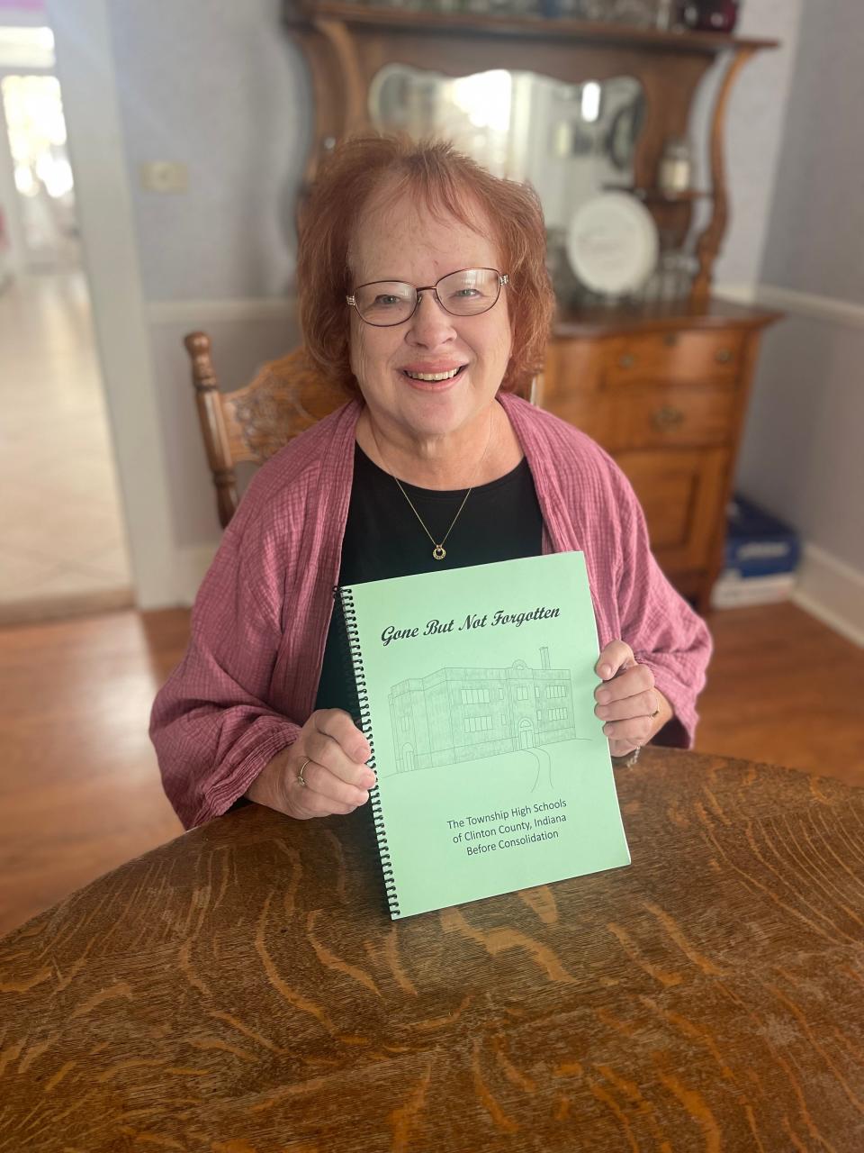 Reta Williams inside her Clinton County home with the book she compiled remembering old school fight songs.