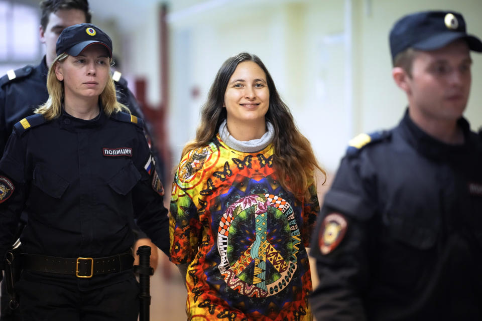 Sasha Skochilenko, a 33-year-old artist and musician, walks escorted by officers to the court room for a hearing in the Vasileostrovsky district court in St. Petersburg, Russia, on Thursday, Oct. 19, 2023. Skochilenko was arrested in April 2022 and faces charges of spreading false information about the army after replacing supermarket price tags with slogans protesting against Russia's military operation in Ukraine. (AP Photo/Dmitri Lovetsky)