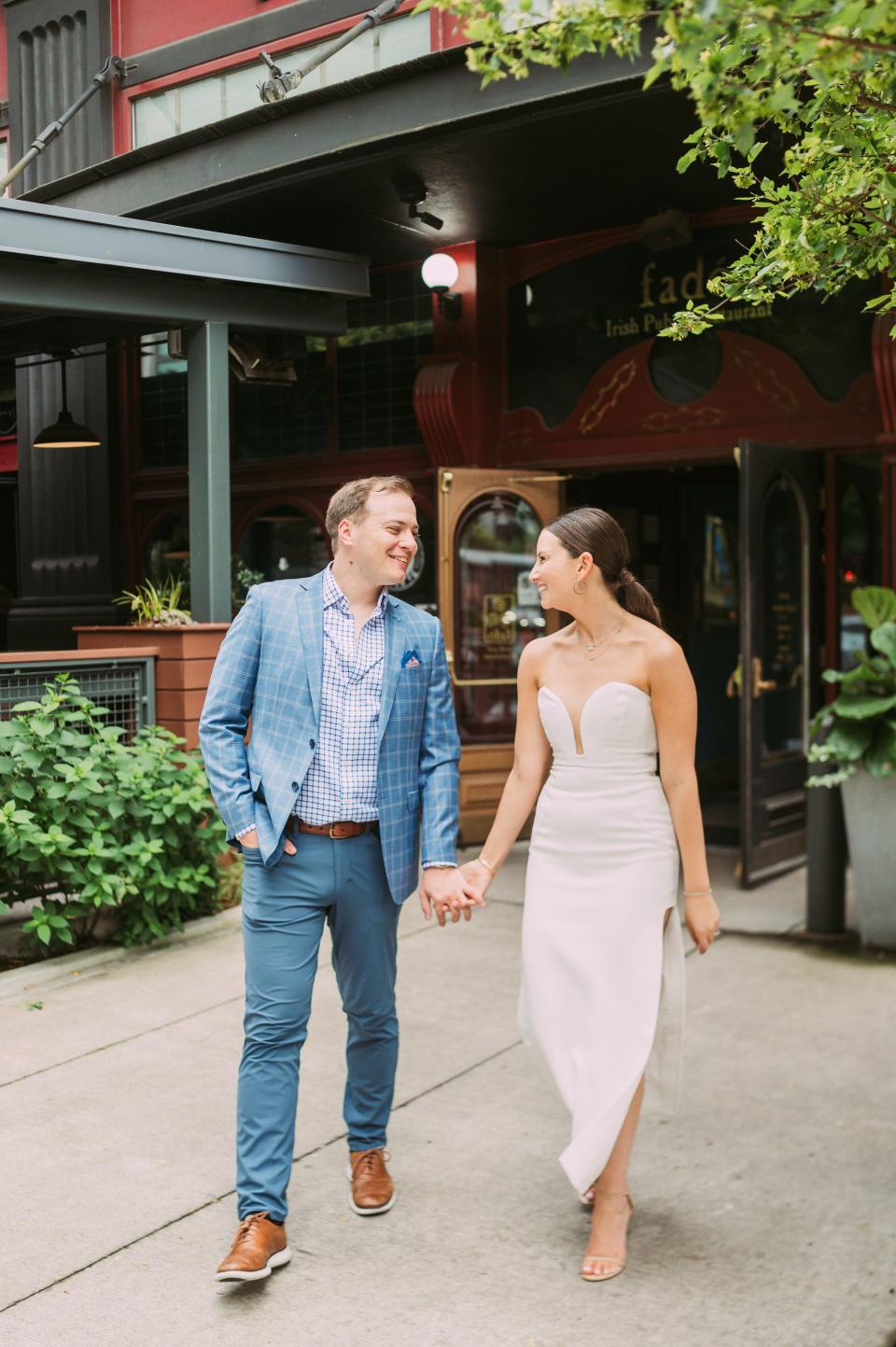 A bride and groom hold hands and walk together.