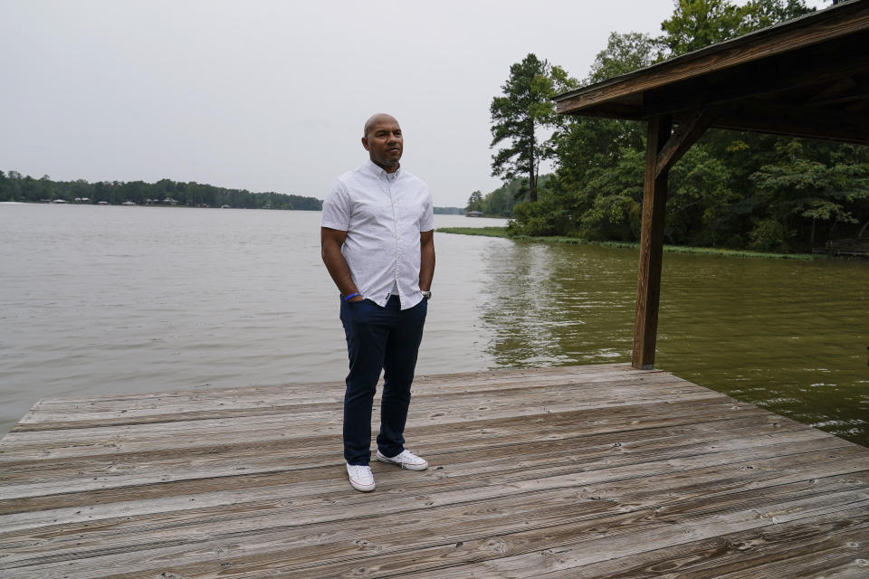 Hancock County coroner Adrick Ingram, 44, of Sparta, poses for a portrait on a deck next to a lake, Saturday, Sept. 19, 2020, in Sparta, Ga. The number of COVID-19 deaths in Hancock County is the highest per-capita rate of any U.S. county. ''It has affected our community in a way that I consider tragic," Ingram says. (AP Photo/Brynn Anderson)