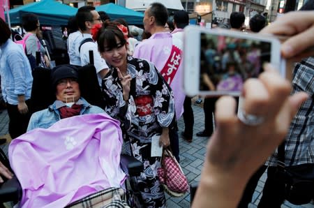 A woman takes a photo with Reiwa Shinsengumi's disabled candidate for Japan's July 21 upper house election Yasuhiko Funago, who has ALS, at his election rally in Tokyo