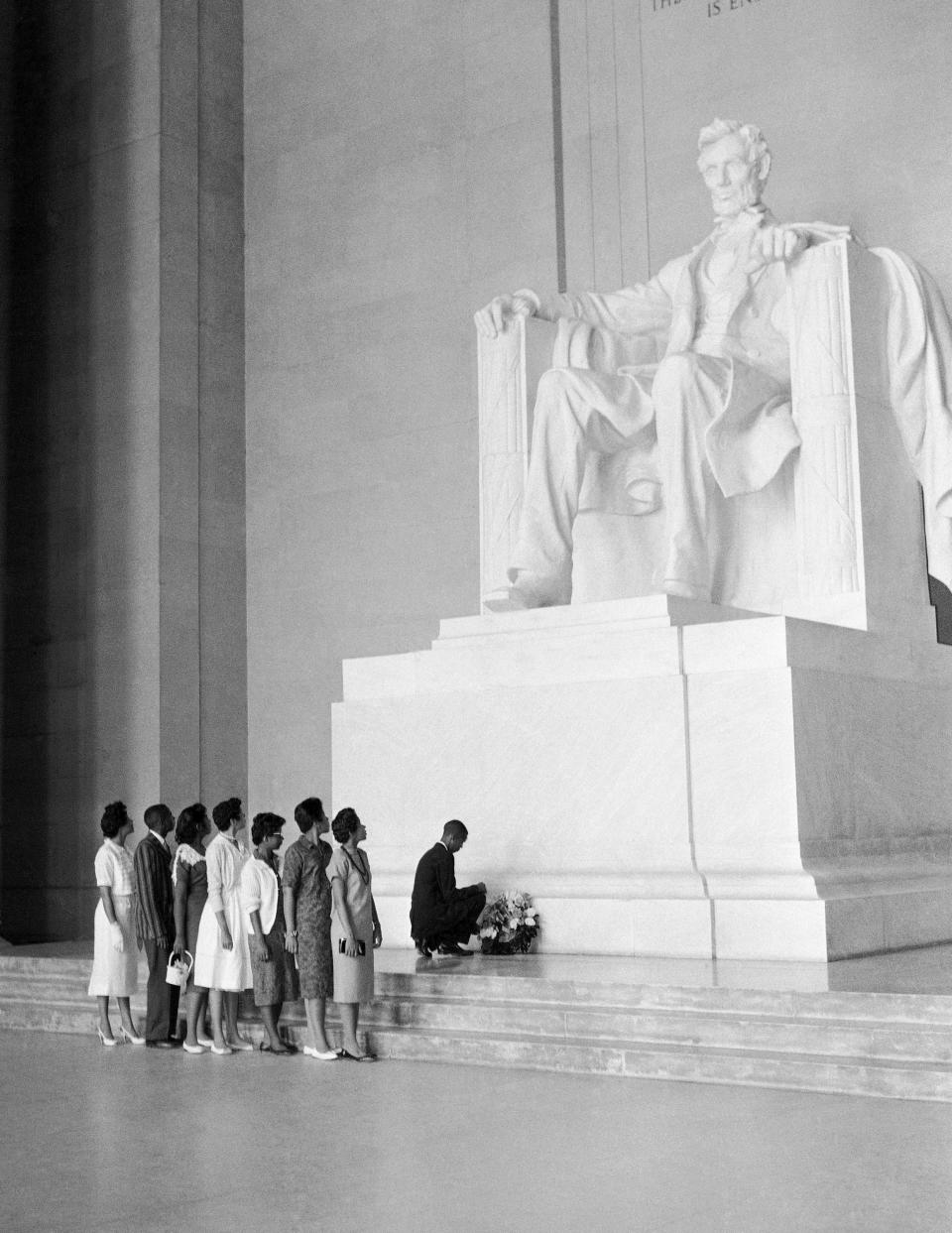 FILE - The statue of Abraham Lincoln dwarfs seven Black students from Central High School in Little Rock, Ark., as one of the students, Terrance Roberts, places a wreath at the statue's base during a visit to the Lincoln Memorial, Aug. 26, 1958, in Washington. From left, Mrs. L.C. Daisy Bates, Jefferson Thomas, Melba Pattillo, Carlotta Walls, Elizabeth Eckford, Minniejean Brown, Gloria Ray, and Terrence Roberts. (AP Photo/William J. Smith)