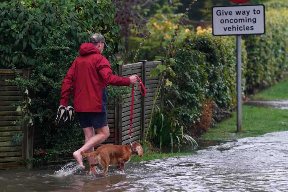 A man walks his dog on a flooded road in Willersley village, Gloucestershire. An amber weather warning for heavy rain has come into force in parts of England, with the Met Office warning that affected areas could experience more than a month's worth of rain falling on Monday. Picture date: Monday September 23, 2024.