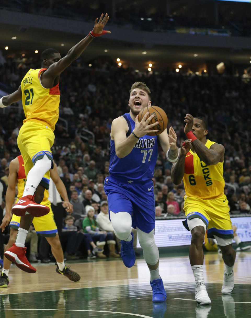 Dallas Mavericks' Luka Doncic (77) shoots between Milwaukee Bucks' Eric Bledsoe (6) and Tony Snell during the first half of an NBA basketball game Monday, Jan. 21, 2019, in Milwaukee. (AP Photo/Aaron Gash)