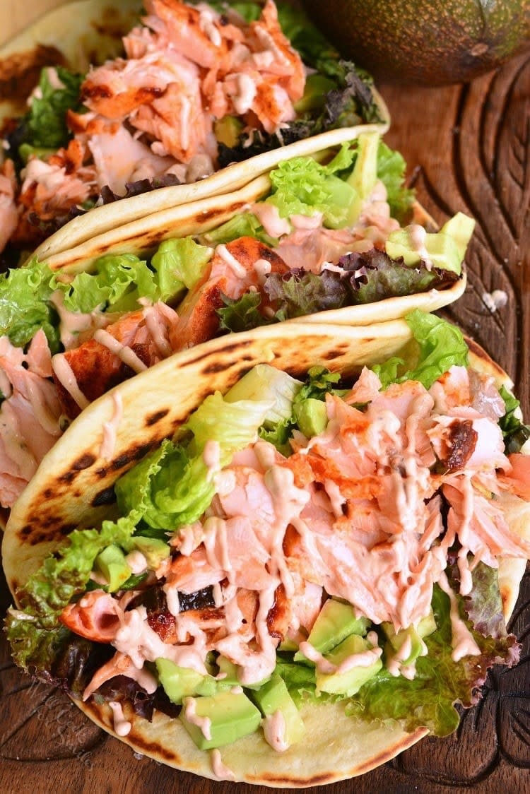 Salmon tacos with avocado, lettuce, and spicy mayo drizzle.