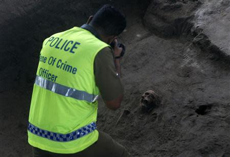 A police officer takes a picture of a human skull at a construction site in the former war zone in Mannar, about 327 km (203 miles) from the capital Colombo, January 16, 2014. REUTERS/Dinuka Liyanawatte