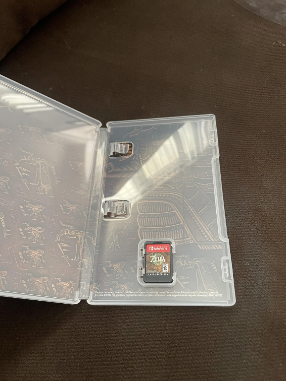The image shows a clear plastic Nintendo Switch game case opened, with a single game cartridge for "The Legend of Zelda: Tears of the Kingdom" inside