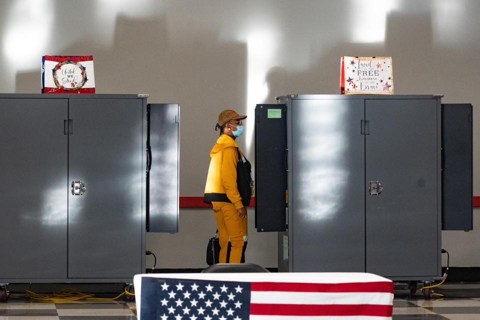 A voter in a mask at a metal booth.