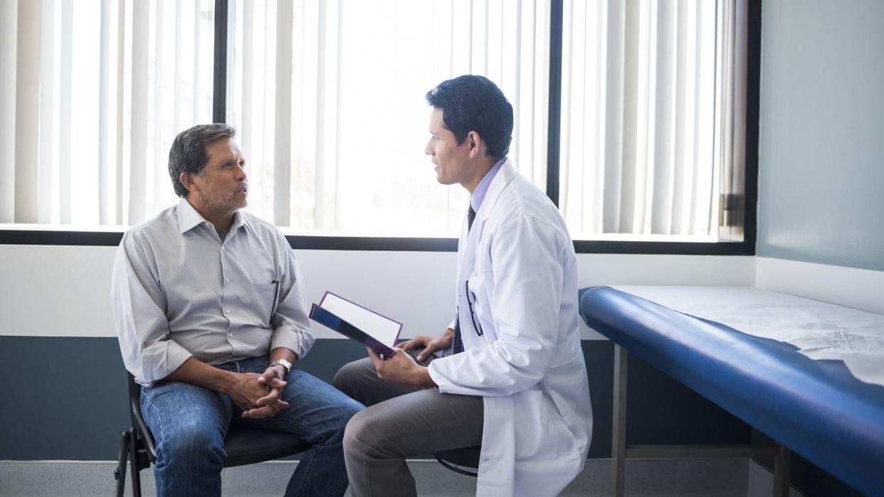 side view of doctor talking with senior patient in hospital