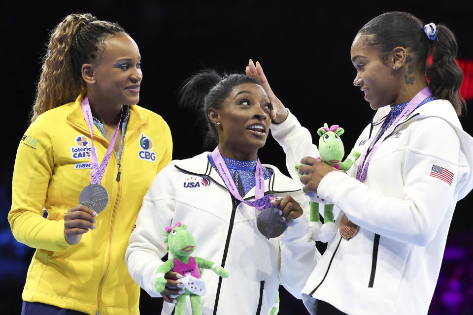 United States' Simone Biles, center and gold medal, Brazil's Rebeca Andrade, left and silver medal and United States' Shilese Jones, right and bronze medal, react on the podium after the women's all-round final at the Artistic Gymnastics World Championships in Antwerp, Belgium, Friday, Oct. 6, 2023. (AP Photo/Geert vanden Wijngaert)