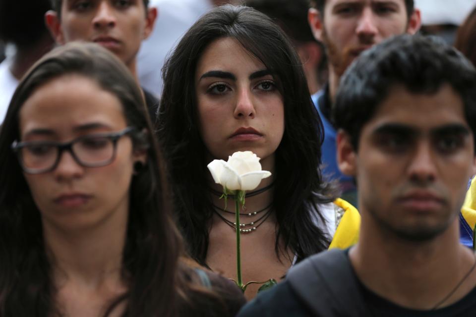 A protester carries a white flower during a silent protes - Credit: Fernando Llano/AP