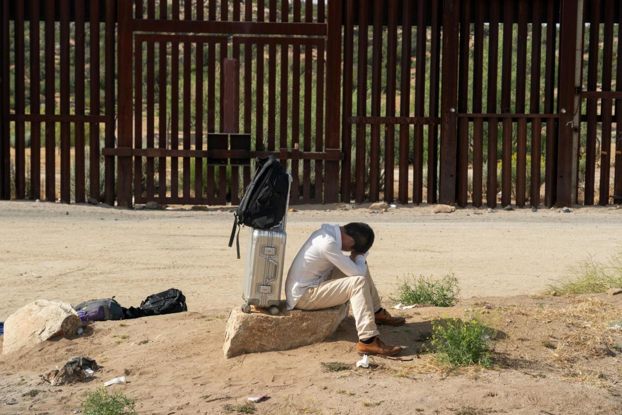 <span>An asylum-seeking migrant from China rests on a rock while waiting to be transported by the US border patrol after crossing the border from Mexico into Jacumba Hot Springs, California, on 4 June 2024.</span><span>Photograph: Go Nakamura/Reuters</span>