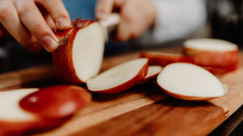 Person slicing apple cutting board