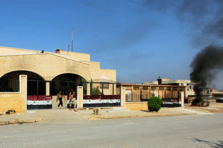 Rebel fighters from the hardline jihadist Jund al-Aqsa walk out from a building with Syrian national flag painted on its gate in Taybat al Imam town after they advanced in the town in Hama province, Syria August 31, 2016. REUTERS/Ammar Abdullah