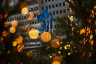 European Union flags, seen through Christmas decoration lights, flutter in the wind outside the European Commission headquarters in Brussels, Saturday, Dec. 12, 2020. British Prime Minister Boris Johnson and European Commission President Ursula von der Leyen have set a Sunday deadline to decide whether to keep talking or prepare all-out for a no-deal break. (AP Photo/Francisco Seco)