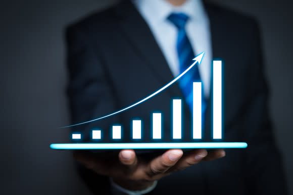 Businessman holding a tablet computer and growing chart floating above digital tablet computer screen