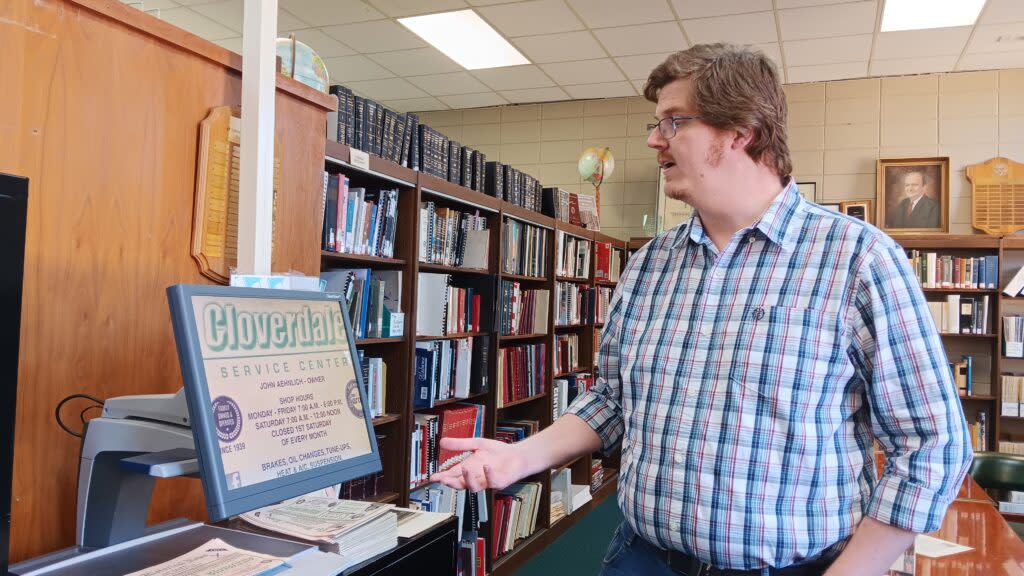 A man in a checkered shirt at a computer