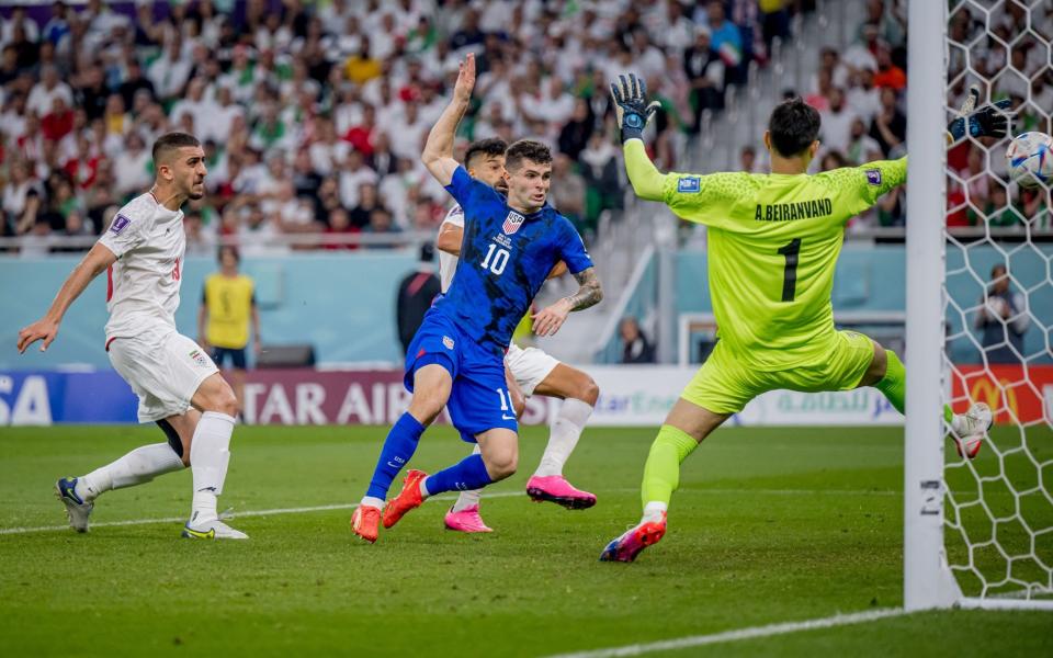 Christian Pulisic (C) of USA scores his team's first goal past Majid Hosseini (L), Alireza Beiranvand (R) and Amir Abedzadeh of Iran during the FIFA World Cup Qatar 2022 Group B match between IR Iran and USA at Al Thumama Stadium - Marvin Ibo Guengoer/Getty Images