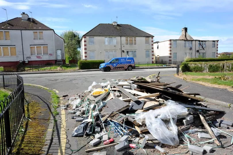 Tonnes of rubbish is dumped on a road in front of boarded up homes in the Tannahill area