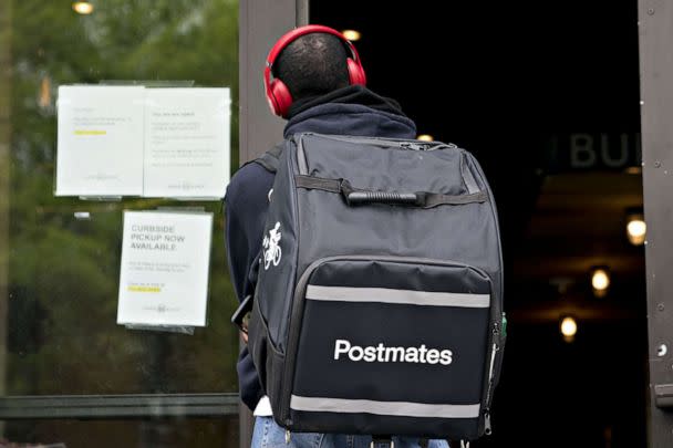 PHOTO: A Postmates Inc. delivery person stands outside a restaurant in Washington, D.C., on April 20, 2020. (Andrew Harrer/Bloomberg via Getty Images, FILE)
