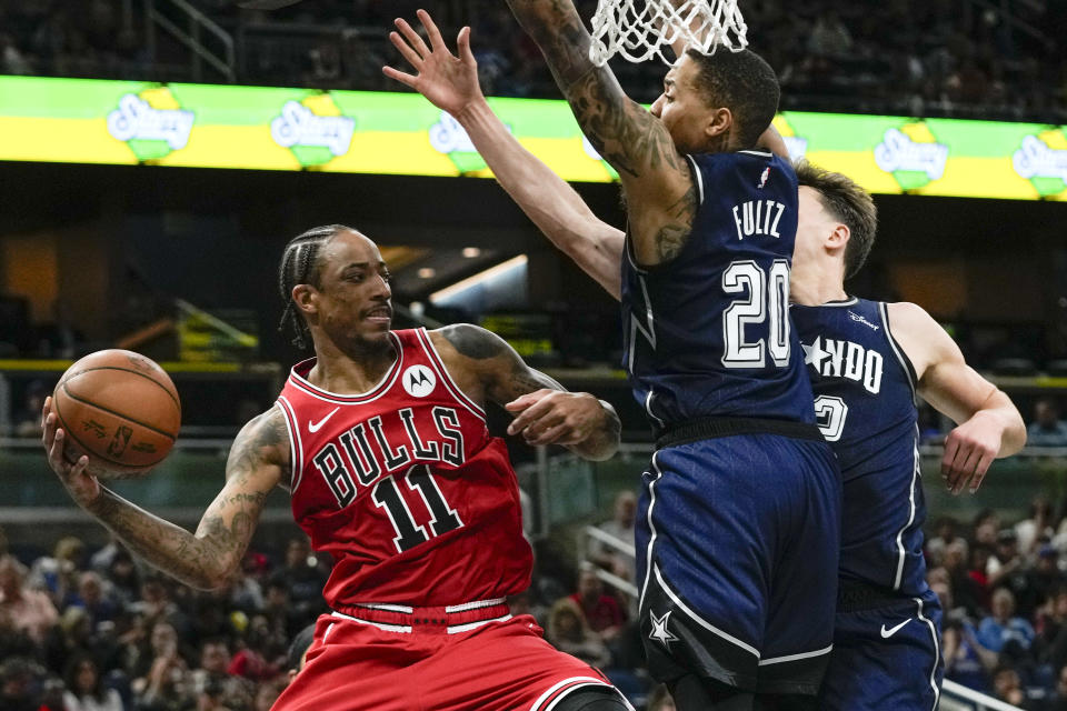 Chicago Bulls forward DeMar DeRozan (11) passes the ball as Orlando Magic guard Markelle Fultz (20) and forward Franz Wagner, right, block his path to the basket during the second half of an NBA basketball game, Saturday, Feb. 10, 2024, in Orlando, Fla. (AP Photo/John Raoux)