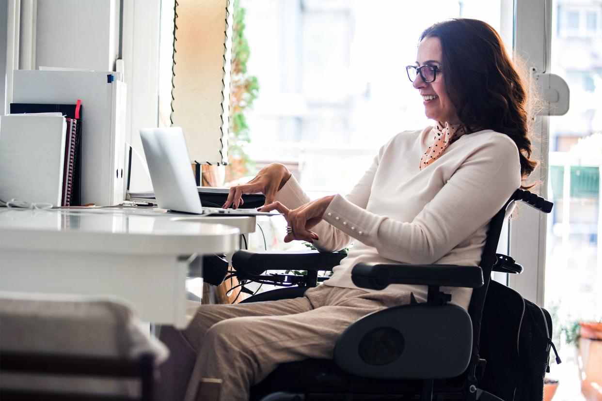 Woman in a wheelchair smiling while on her computer