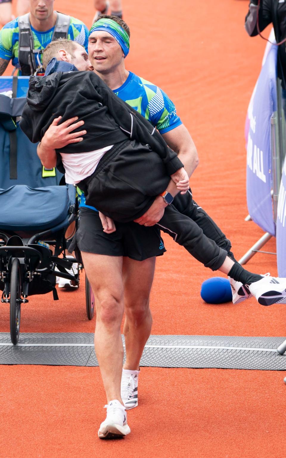 Kevin Sinfield carries his friend and former teammate Rob Burrow across the finish line of the Leeds Marathon in 2023