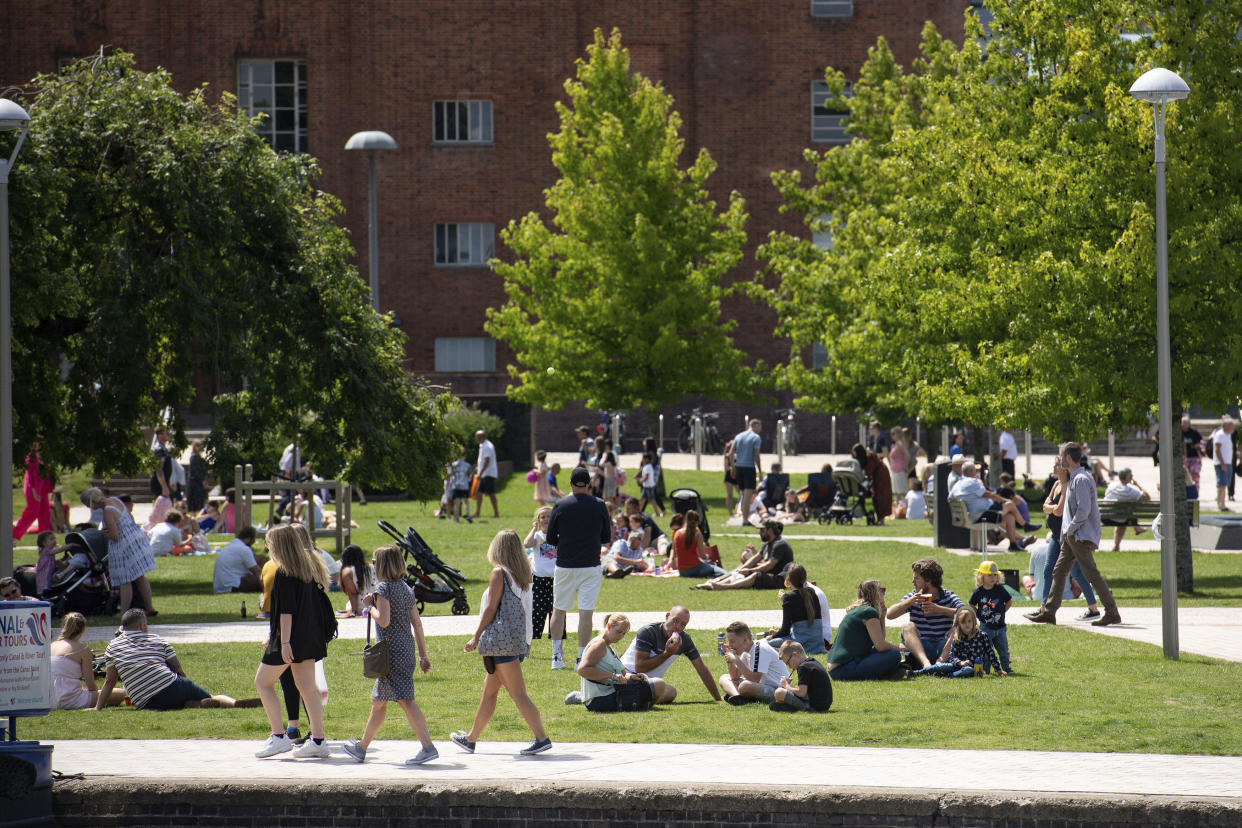 People sit on the grass outside the Royal Shakespeare Theatre on a warm day in Stratford-upon-Avon, England, Sunday July 12, 2020. (Jacob King/PA via AP)