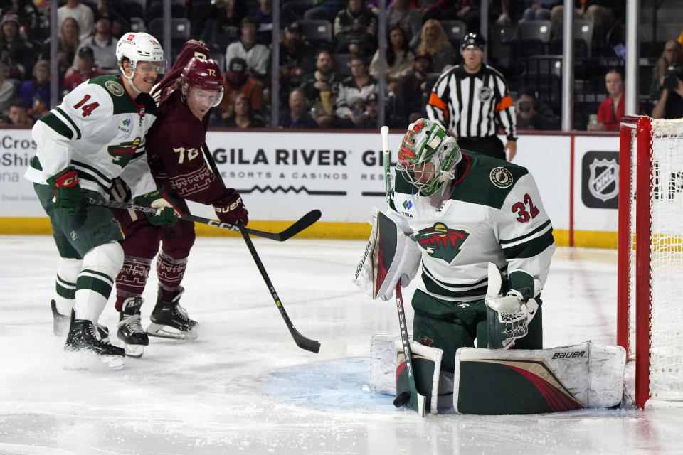 Minnesota Wild goaltender Filip Gustavsson, right, makes a save in front of Wild center Joel Eriksson Ek (14) and Arizona Coyotes center Travis Boyd (72) in the second period during an NHL hockey game, Sunday, March 12, 2023, in Tempe, Ariz. (AP Photo/Rick Scuteri)