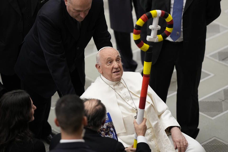 Pope Francis is presented with a pastoral staff made in Uganda as he salutes faithful and pilgrims at the end of his weekly general audience in the Paul VI Hall, at the Vatican, Wednesday, Feb. 28, 2024. (AP Photo/Andrew Medichini)