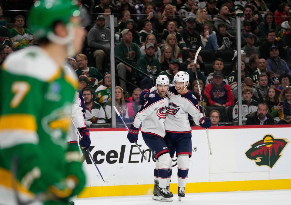 Columbus Blue Jackets center Adam Fantilli, center left, celebrates with defenseman Damon Severson, center right, after scoring during the third period of an NHL hockey game against the Minnesota Wild, Saturday, Oct. 21, 2023, in St. Paul, Minn. (AP Photo/Abbie Parr)