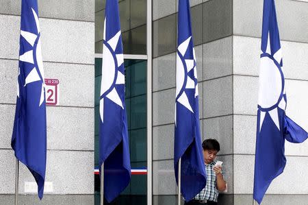 A man looks at his smartphone behind the Nationalist Kuomintang Party flags at its headquarters in Taipei, Taiwan, October 16, 2015. REUTERS/Pichi Chuang