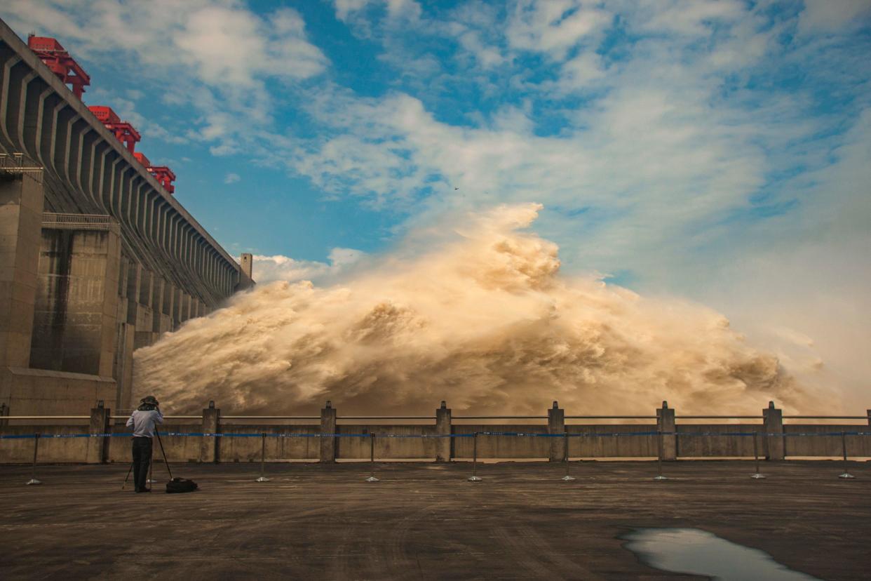 A person takes photos as water is released from the Three Gorges Dam, a gigantic hydropower project on the Yangtze River, to relieve flood pressure in Yichang, central China's Hubei province,   July 19, 2020. / Credit: STR/AFP/Getty