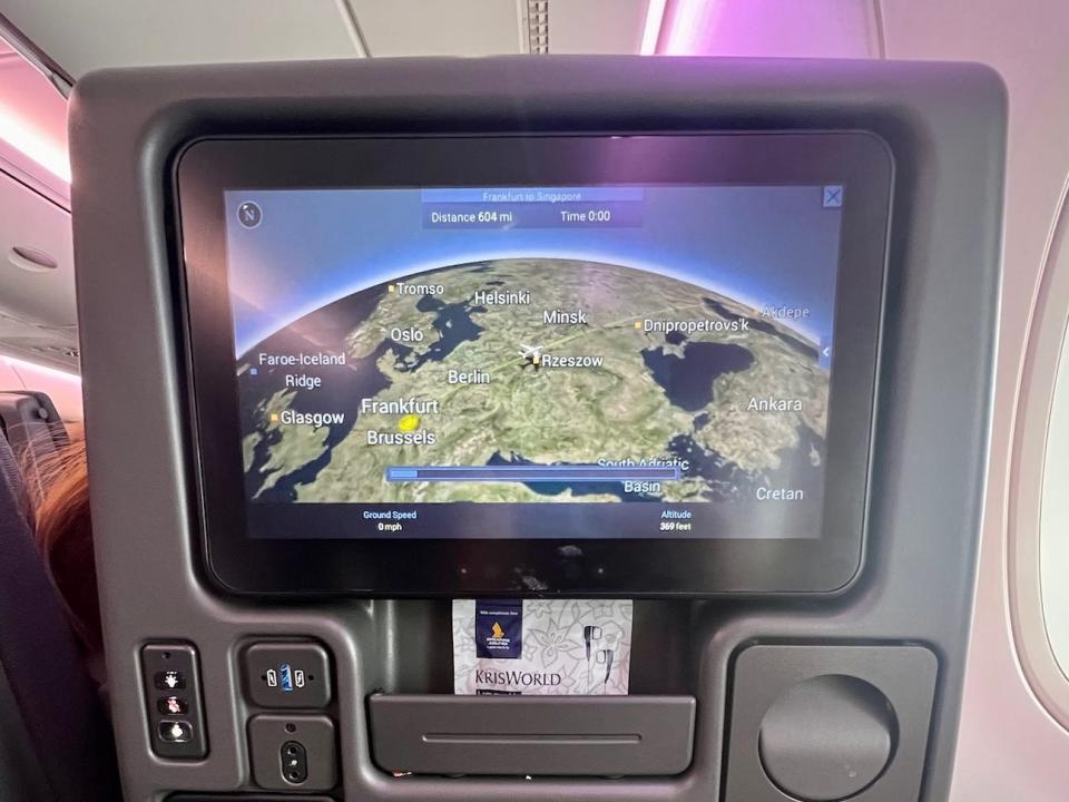 A view of the full seatback, with the TV, cupholder, USB, and cubby. The screen has a globe on it.