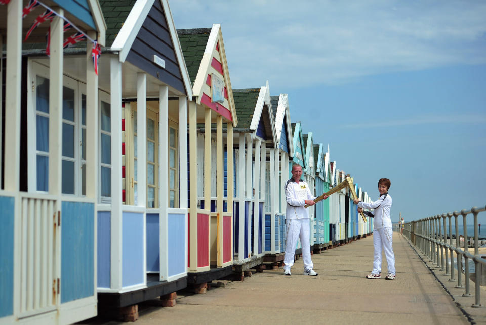 Caroline Emeny and Richard Game carry the Olympic torch past the beach huts on Southwold sea front on July 5, 2012 in Southwold, England. The Olympic Flame is now on day 48 of a 70-day relay involving 8,000 torchbearers covering 8,000 miles. (Photo by Jamie McDonald/Getty Images)