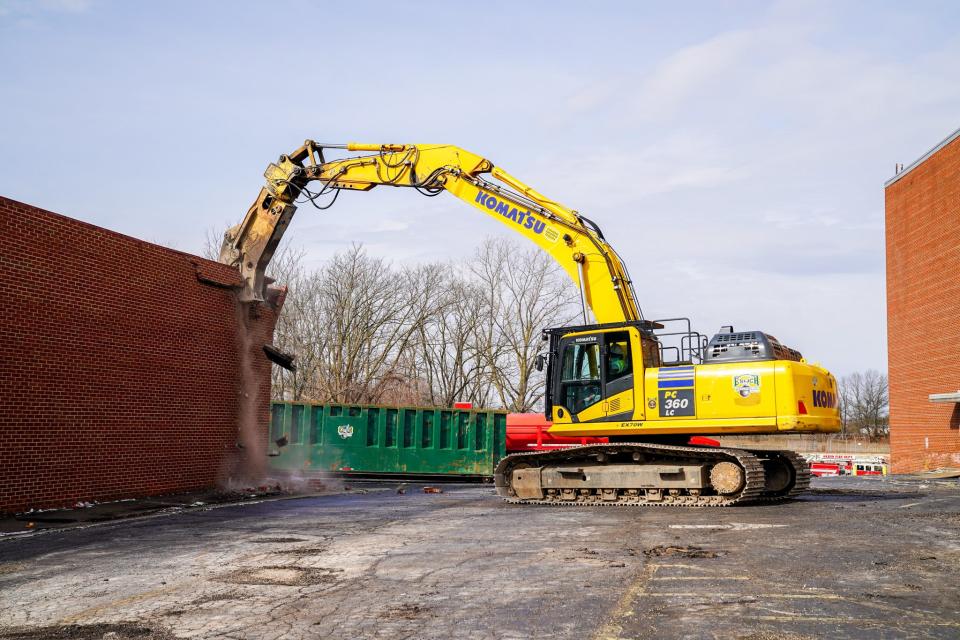 An excavator rips into a detached garage at the site of the former Akron Baptist Temple, marking the start of the building's demolition.