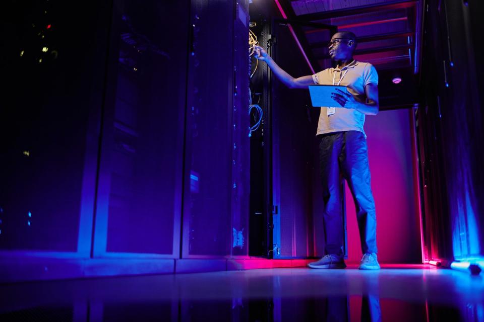 A system administrator sets up a server network in a neon-lit data center.