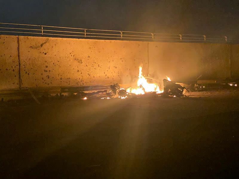 Burning debris are seen on a road near Baghdad International Airport